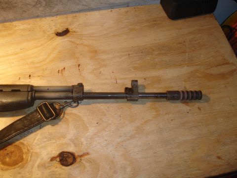 1989 Ford Bronco - A firearm is shown on a wooden surface, with a leather strap attached. The muzzle end has a ribbed design.