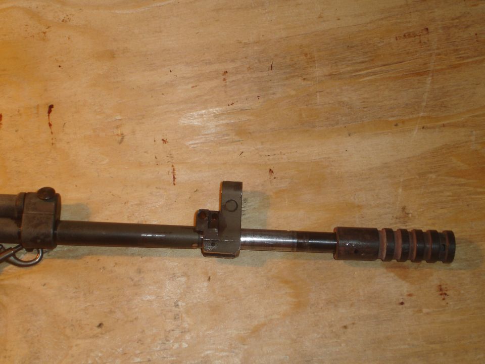 Close-up of a firearm barrel with front sight assembly and a ribbed end