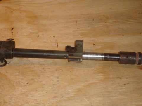 1989 Ford Bronco - This image shows a close-up view of a metal component, likely from a firearm, resting on a wooden background.