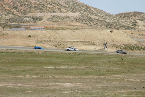 1995 Ford Taurus - Multiple vehicles are seen on a race track with a person standing nearby.