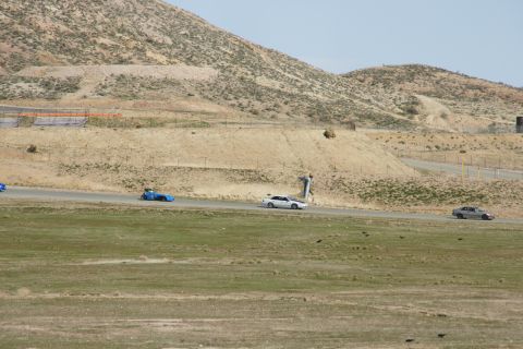 1995 Ford Taurus - A white sedan races on a track with a blue car and a silver car visible in the distance.