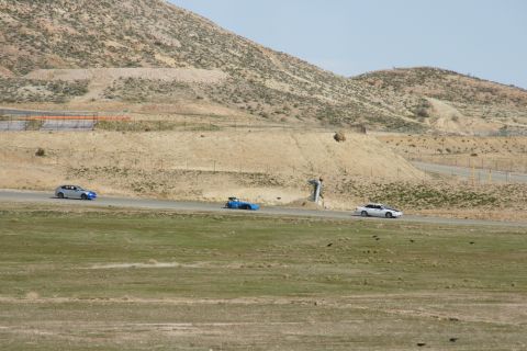 1995 Ford Taurus - Cars race on a track in a dry, hilly landscape.