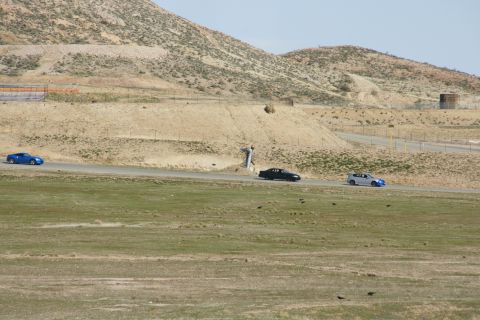 1995 Ford Taurus - Multiple vehicles on a road in a barren, hilly landscape.