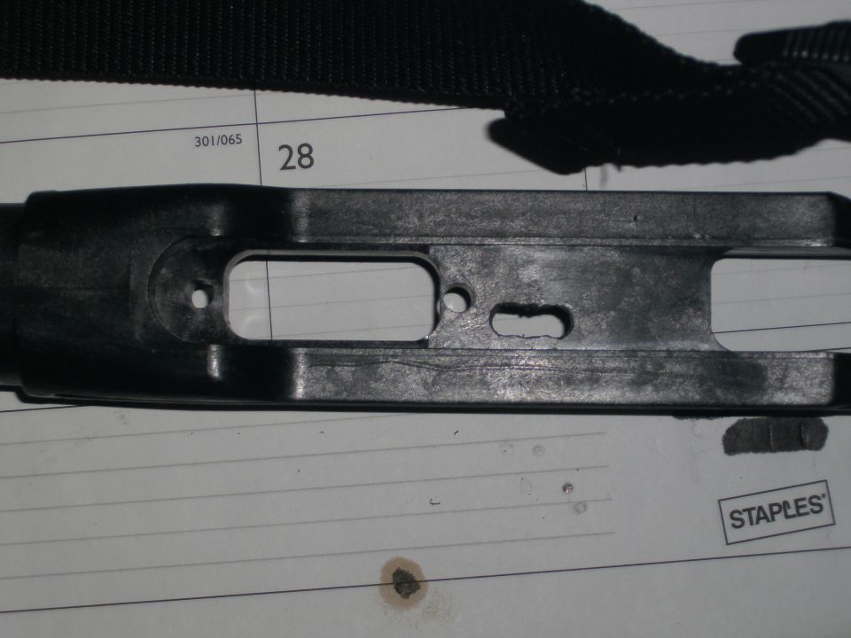 Black metal firearm receiver part on lined paper with Staples logo