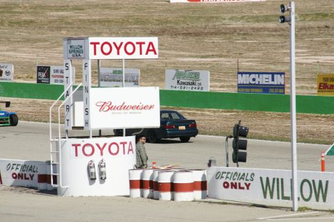 1995 Ford Taurus - A dark sedan is parked near the finish line at Willow Springs International Raceway, with Toyota and Budweiser signage visible.