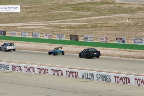 1995 Ford Taurus - Three vehicles on a race track, with sponsor signs visible in the background.
