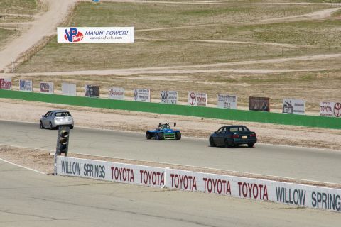 1995 Ford Taurus - Multiple vehicles are seen on a race track with various sponsor signs visible in the background.