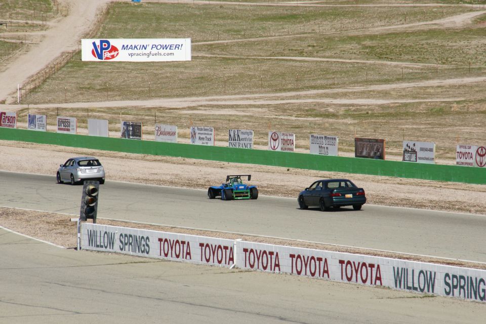 Cars on a race track with signs for VP Racing Fuels and Toyota