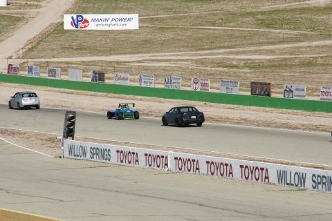 1995 Ford Taurus - Multiple vehicles race on a track with sponsor advertisements lining the course.