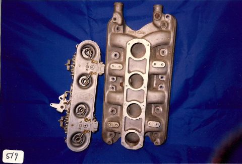 1973 Ford Mustang - A four-barrel carburetor sits next to an aluminum intake manifold, both automotive engine parts.
