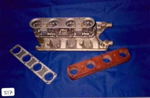 1973 Ford Mustang - A carburetor manifold assembly with two accompanying gaskets is displayed against a blue backdrop.