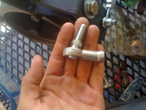 1978 Ford Bronco - A hand holds a metal rod end joint, a component likely for a vehicle's linkage or suspension system.