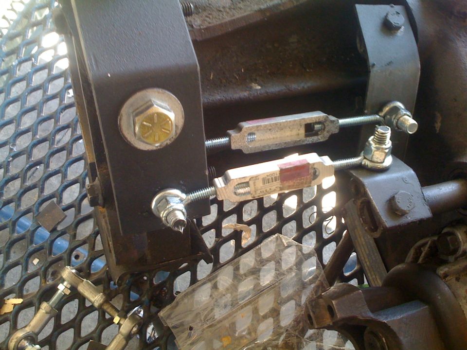 Close-up of transfer case linkage with two turnbuckles and hardware