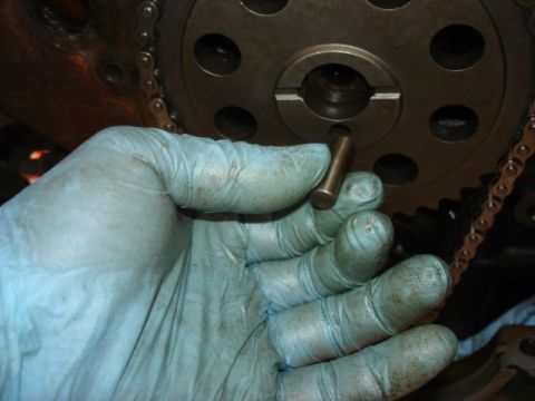1992 Ford Bronco - A gloved hand holds a pin next to a vehicle's engine timing chain and gear assembly.