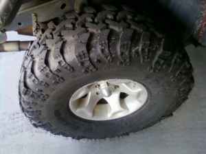 1990 Ford Bronco - Off-road tire and wheel assembly with Supermotors.net branding visible.