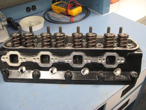2008 Ford F-250 - A black engine cylinder head with multiple valve springs is shown on a workbench with tools in the background.