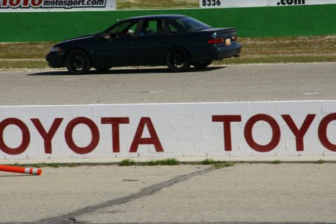 1995 Ford Taurus - A 1995 Ford Taurus sedan seen on a racetrack, with Toyota branding on a wall.