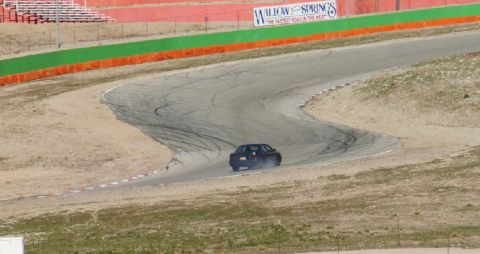 1995 Ford Taurus - A dark sedan drifts around a corner on a race track, leaving tire marks.