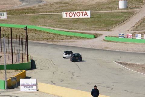 1995 Ford Taurus - A dark sedan and a white sedan race on a track with a large Toyota sign visible.