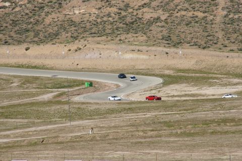 1995 Ford Taurus - Several cars are seen on a race track, including a red sports car navigating a curve.