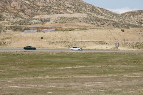 1995 Ford Taurus - Two sedans are seen driving on a road in a dry, hilly landscape.