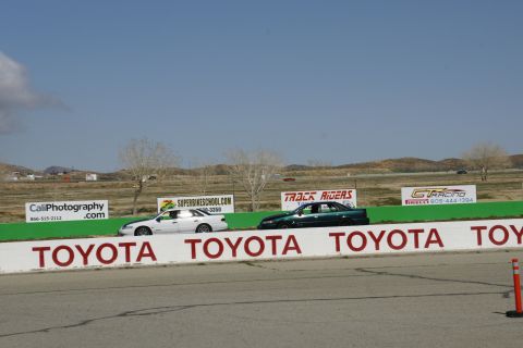 1995 Ford Taurus - Two sedans are seen on a race track, with prominent Toyota branding on the barrier in the foreground.