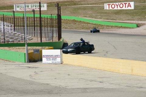 1995 Ford Taurus - Race track scene with a sedan and a small vehicle. Toyota sign in background.