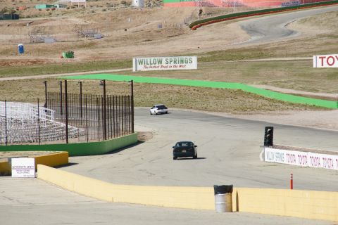 1995 Ford Taurus - Two cars are driving on a race track at Willow Springs. The sign says "Willow Springs The Fastest Road in the West."