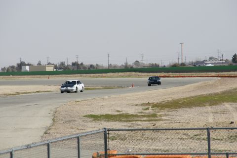 1995 Ford Taurus - Two cars race on a track under a hazy sky.