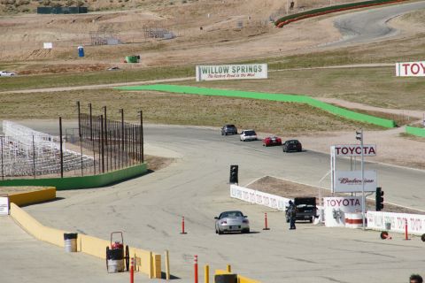 1995 Ford Taurus - A race track scene at Willow Springs, multiple cars on the track and prominent Toyota branding.