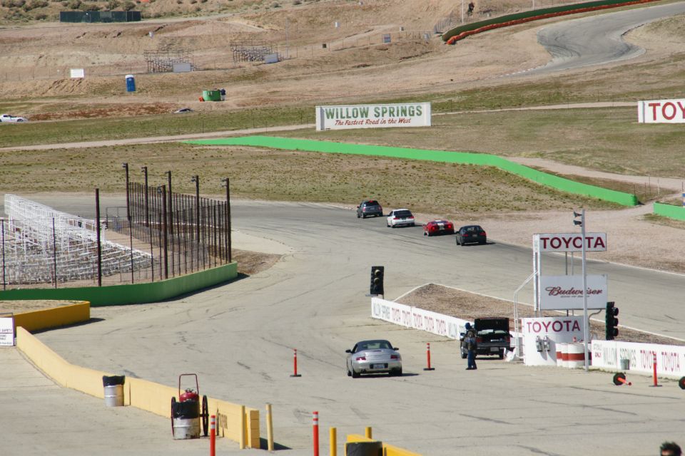 Race track scene with multiple cars, Toyota signage, and Willow Springs banner