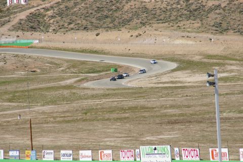 1995 Ford Taurus - Multiple vehicles navigate a turn on a race track, with various sponsor signs visible in the foreground.