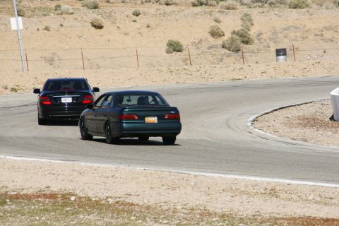 1995 Ford Taurus - A dark green 1995 Ford Taurus sedan navigates a turn on a race track, with another car behind it.