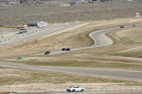 1995 Ford Taurus - Multiple vehicles are seen on a winding race track, with a white sports car prominent in the foreground.