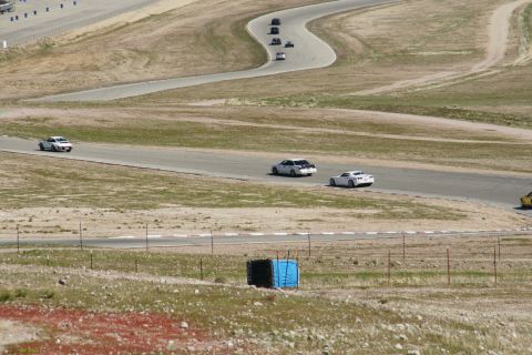 1995 Ford Taurus - Cars navigate a challenging turn on a sun-drenched race track.
