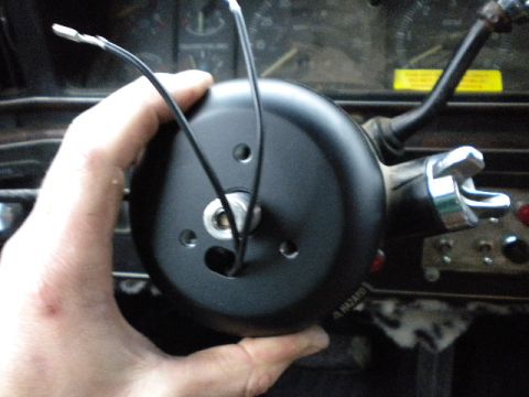1989 Ford Bronco - A person is holding a black steering column cover with wires in a vehicle's interior.