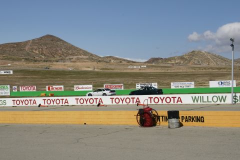 1995 Ford Taurus - A race track scene with cars on the track and mountains in the distance.