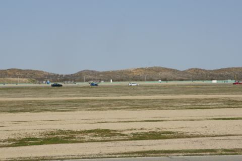 1995 Ford Taurus - Cars are seen on a race track under a clear sky with distant hills.