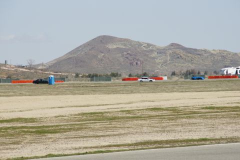 1995 Ford Taurus - A black car, a white car, and a blue car are visible on a racetrack with a mountain range in the distance.