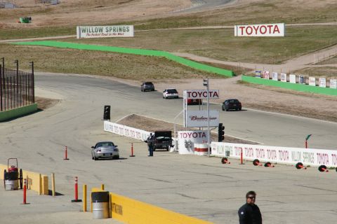 1995 Ford Taurus - Multiple vehicles are on the Willow Springs International Raceway, with various sponsor signs visible around the track.