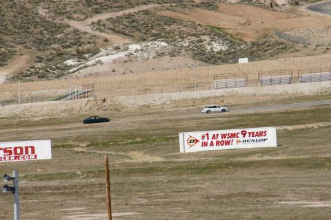 1995 Ford Taurus - Two sedans are seen on a race track with grandstands in the background and advertising banners in the foreground.