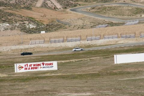 1995 Ford Taurus - A race track scene features two cars driving on the asphalt, with a large Dunlop banner visible in the foreground.