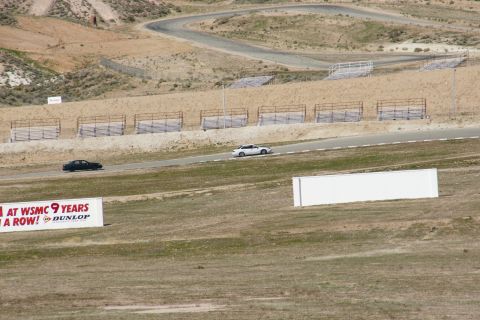 1995 Ford Taurus - Two sedans drive on a race track with grandstands and a Dunlop banner visible.