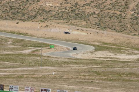 1995 Ford Taurus - Two cars navigate a serpentine road course under a bright sky, with arid hills in the background.