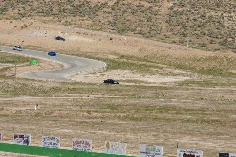 1995 Ford Taurus - Cars navigate a challenging race track under a bright sky, with spectators visible in the foreground.