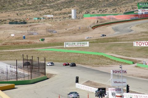 1995 Ford Taurus - Cars race on a track at Willow Springs, a sign reads 'Willow Springs The Fastest Road in the West'.