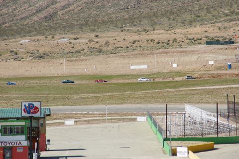 1995 Ford Taurus - A race track scene shows multiple cars on the course, with a pit building in the foreground.
