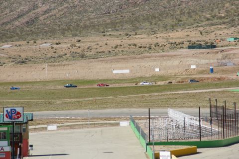 1995 Ford Taurus - Multiple cars are driving on a race track during a sunny day.