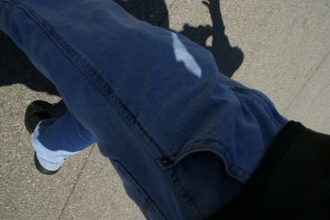 1995 Ford Taurus - A person's legs and shoes are visible, with the shadow of a raised arm cast on the ground.