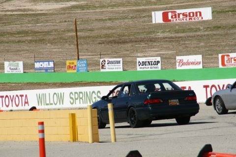 1995 Ford Taurus - Dark 1995 Ford Taurus sedan seen on a race track with other vehicles present.